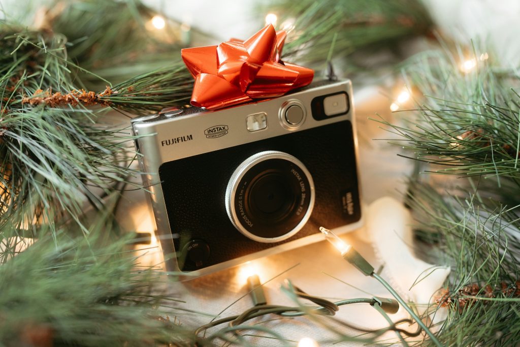 An old style camera with a gift bow on it near a christmas tree to show our festive gift of short financial lessons for founders