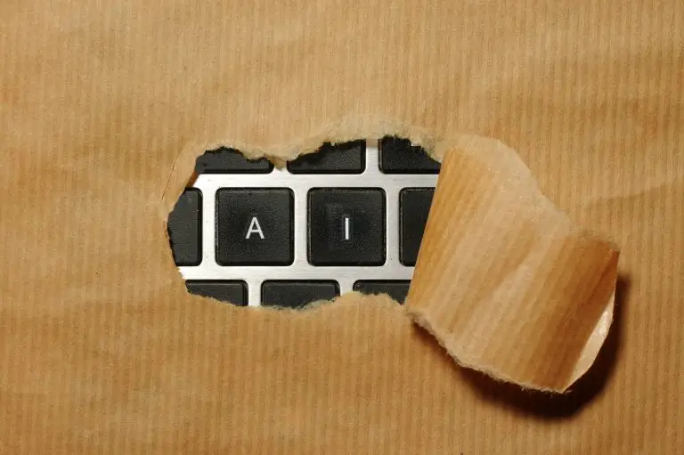 The letters AI on a keyboard peeking through a hole in some brown paper to show the AI risks in finance